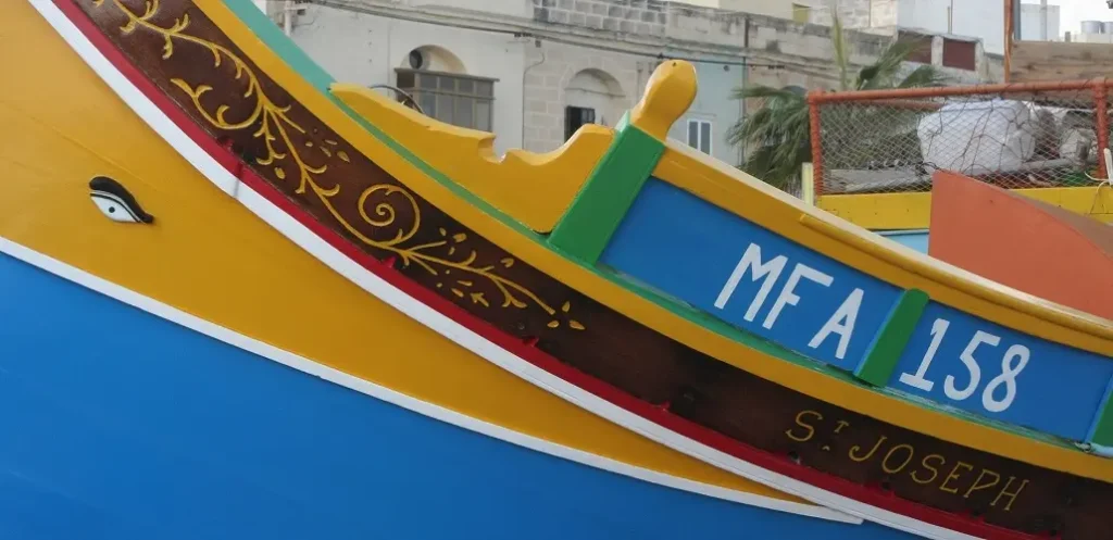 Détail de la peinture d'un Luzzu jaune et bleu du port de Marsaxlokk